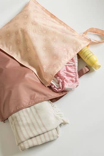 Reusable container  with prima   pattern, holding a yellowish  conduit  and folded pink-striped towel. A hint of cloth  peeks out, suitable for buying  context
