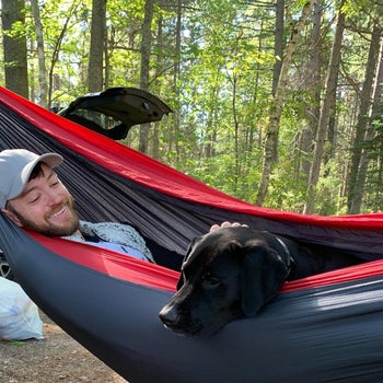 Reviewer laying down in hammock with their dog, smiling