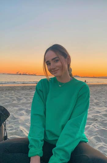 reviewer wearing the green crewneck at the beach