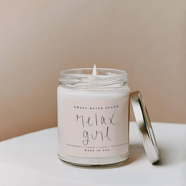 Lit scented candle with the text 'relax, girl' on the label