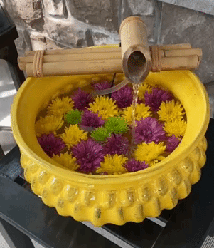 gif of reviewer's bamboo running fountain over a white garden pot filled with flowers