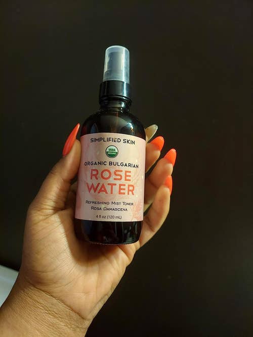 reviewer holding the bottle of rose water 