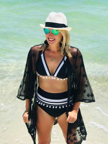 a reviewer in a black bathing suit in white tassels