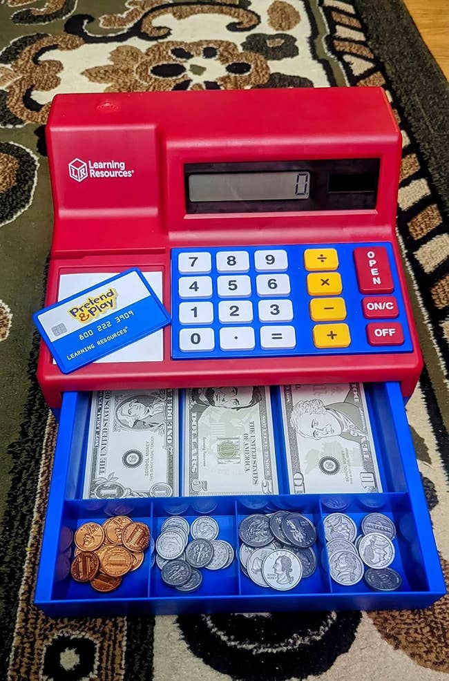The toy cash register with paper money and fake coins in the drawer