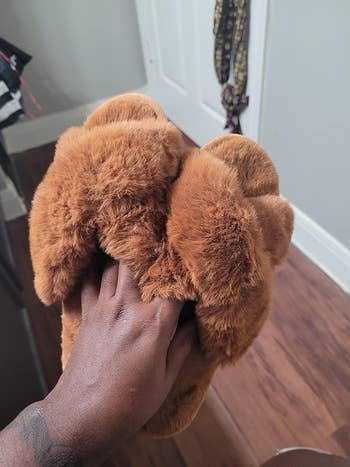 reviewer holding their brown fuzzy slippers