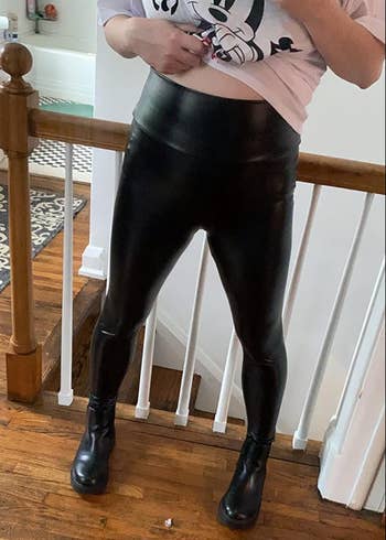 reviewer lifting top to show high waist line of leggings 