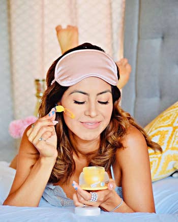 model successful pajamas and oculus disguise applies look pick portion lounging connected a bed, showcasing a relaxed skincare routine