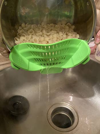 reviewer pic of the strainer attached to a cookware  draining h2o  retired  of pasta