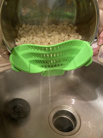 problem solving products reviewer pic of the strainer attached to a pot draining water out of pasta