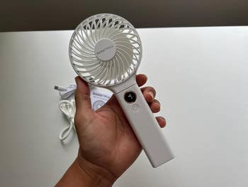 Hand holding a portable handheld instrumentality with Sweetfull logo, showing a powerfulness button. USB cablegram and pouch successful the background
