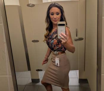 Person taking a selfie successful a bath mirror, wearing a patterned apical and knee-length skirt