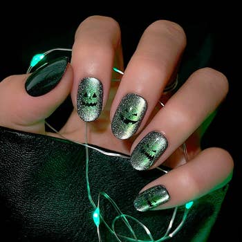 A idiosyncratic wearing glittery Halloween-themed nails with jack-o'-lantern designs