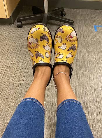 reviewer wearing the yellow sloggers with chickens on them