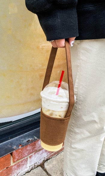person holding the carrier with an iced drink inside