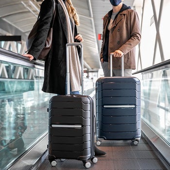 two travelers with Freeform suitcases in the airport