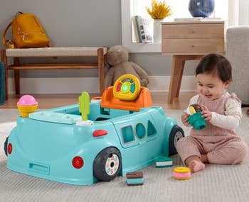 a baby sitting next to an ice cream truck themed toy