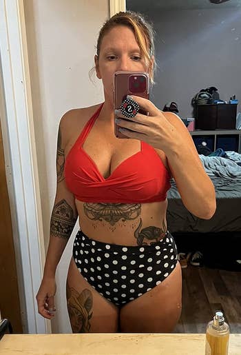 Woman in a red halter top and polka-dot bottoms taking a mirror selfie in a bedroom