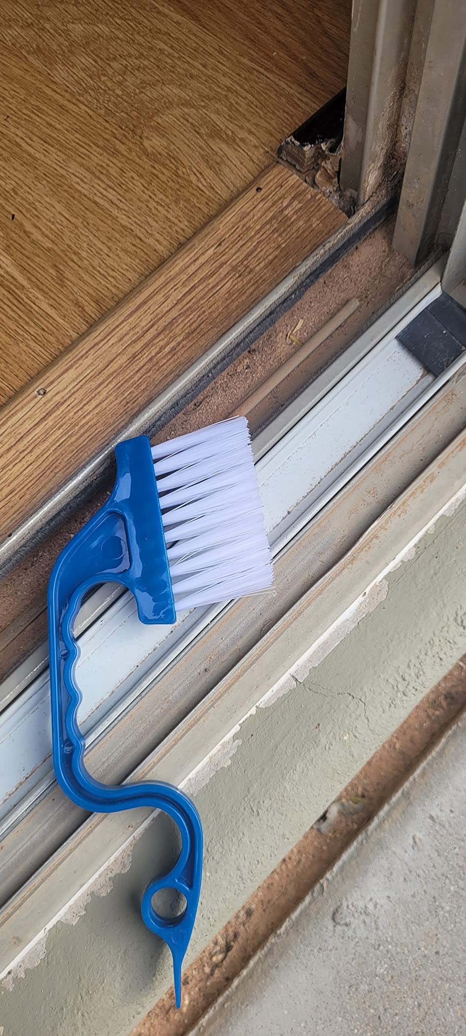 A cleaning brushwood  with a bluish  grip  is resting connected  a model   track, highlighting the buildup of dirt