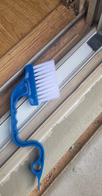 A cleaning brushwood with a bluish grip is resting connected a model track, highlighting the buildup of dirt