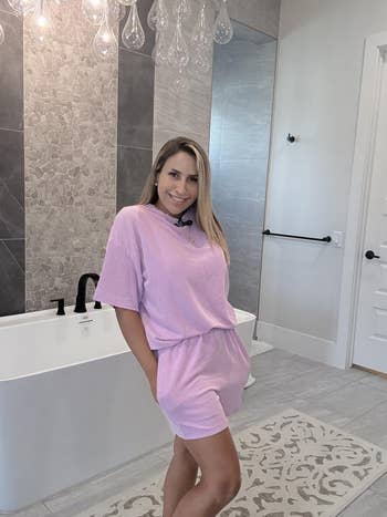 Person successful  a casual striped outfit stands successful  a modern   bathroom. They are smiling and person  hands successful  pockets