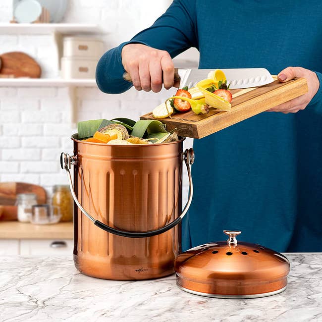 copper compost bin with person putting food scraps inside
