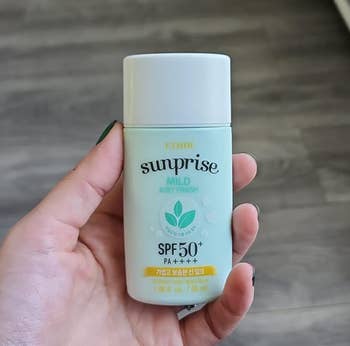Person holding a bottle of sunscreen with SPF 50