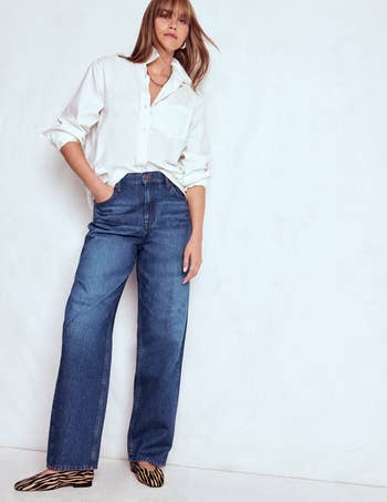 Person wearing a achromatic button-up shirt, bluish wide-leg jeans, and zebra-patterned level shoes