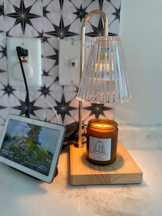 Tablet displaying scenery, modern lamp with transparent shade over lit candle labeled