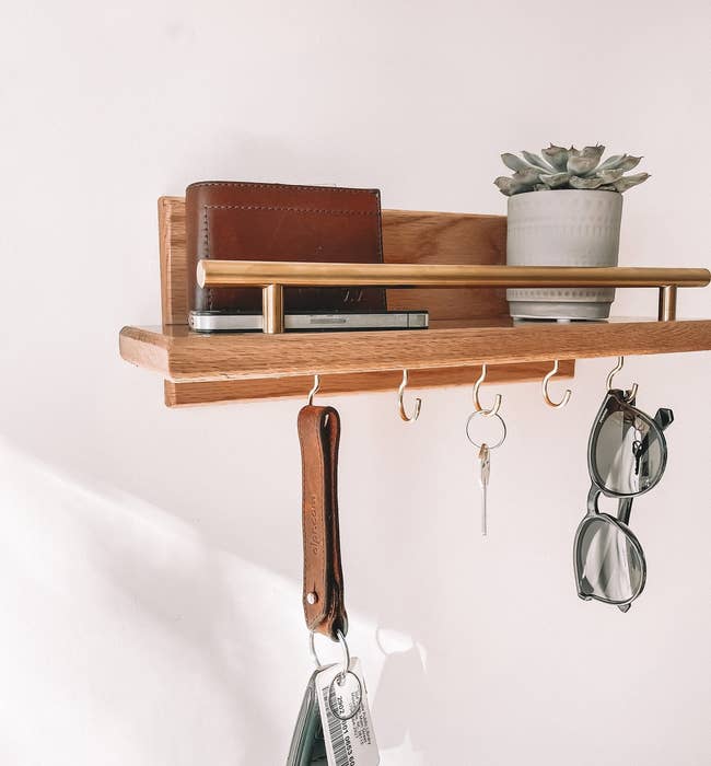the wood organizer on a wall holding keys, a wallet, and other items