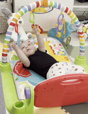 a gif of a baby kicking the fisher price piano