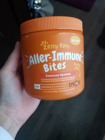 image of reviewer's hand holding container of allergy supplements