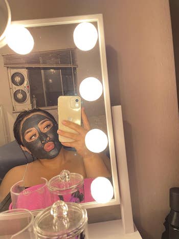 reviewer with face mask on taking selfie in the mirror that's lit up
