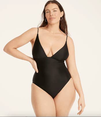 Model in a black strappy V-neck plunging one piece 