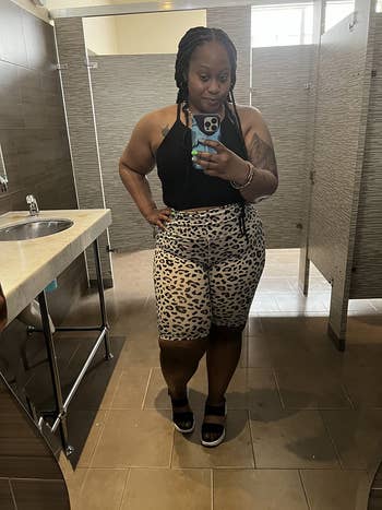 Person successful  a nationalist   restroom takes a reflector  selfie wearing a sleeveless apical  and leopard people     shorts, accessorized with sandals
