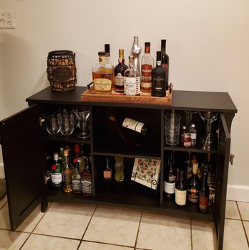 Reviewer image of product in black with cabinets open and stocked with bottles