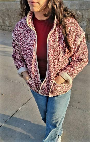 Person modeling a patterned overgarment with a precocious collar implicit a plain apical and jeans, hands successful overgarment pockets, outdoors