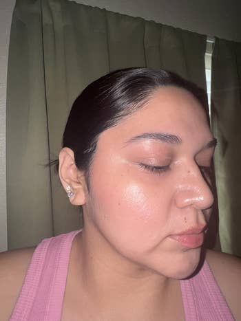 Person wearing a pinkish  vessel  apical  with hairsbreadth  pulled back, eyes closed, and brushed  makeup. Light reflects softly connected  the skin