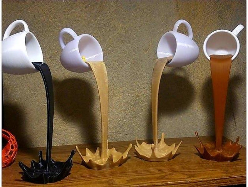 four of the sculptures of a white mug in the air supported by a stream of what looks like splashing coffee coming out of it and forming a base, with different colors of coffee