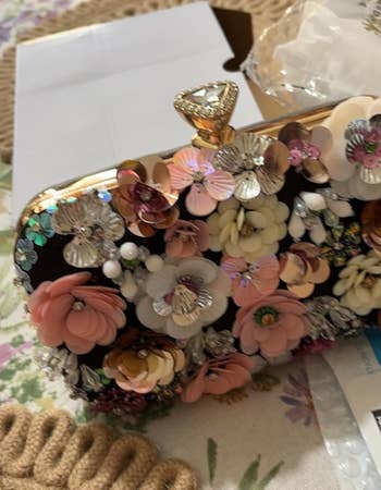 An ornate floral clutch bag with a jewel clasp, indicative of elaborate accessory trends