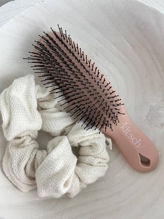 Hairbrush with logo and scrunchie on a bowl, ideal for personal grooming or gifting