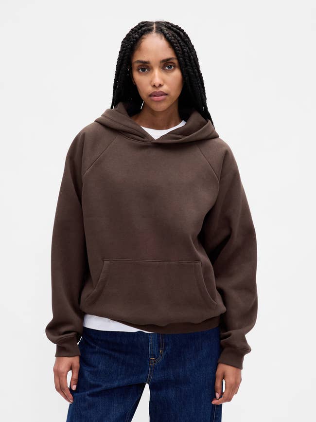 Person wearing a casual hoodie and jeans, lasting against a plain background, featured successful a buying article