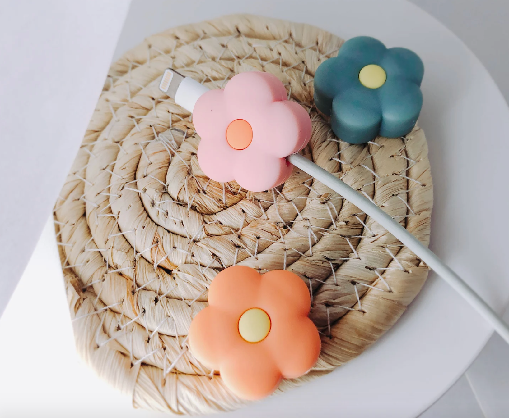 Three flower cable protectors in orange, pink, and blue