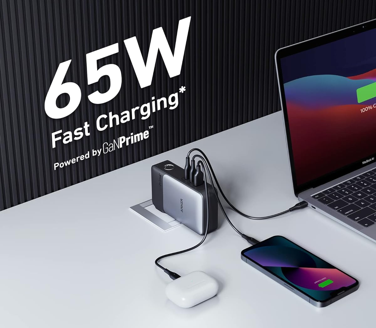 A small gray charger hooked up on a wall charging airpods, a phone, and a laptop 