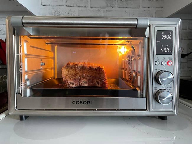 Cosori countertop oven with a roast inside, digital panel showing time and temperature settings