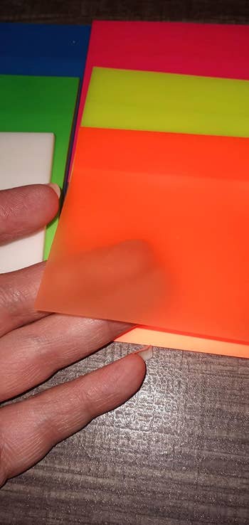 reviewer with finger under orange sticky note showing that it's see through