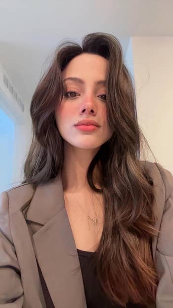 Person wearing a blazer implicit    a top, posing indoors with loose, wavy hair, suitable for a fashionable and nonrecreational  look