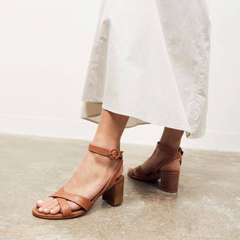 Person wearing white skirt and brown strappy block-heeled sandals