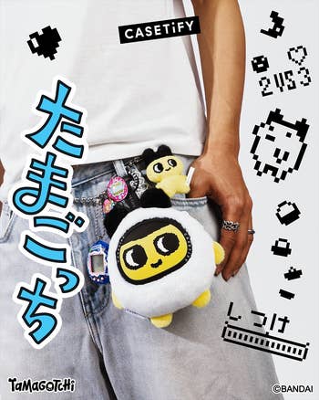 Person holding Tamagotchi-themed telephone  cases and plush toys, wearing jeans with accessories. Branding substance   for CASETiFY and Tamagotchi is visible