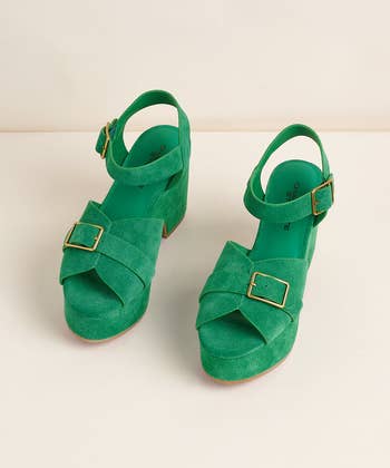 Two green suede platform sandals with ankle straps and gold buckles showcased on a neutral background