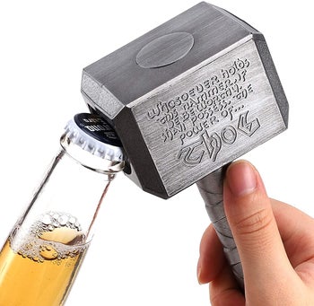 person using the silver hammer to open a glass bottle